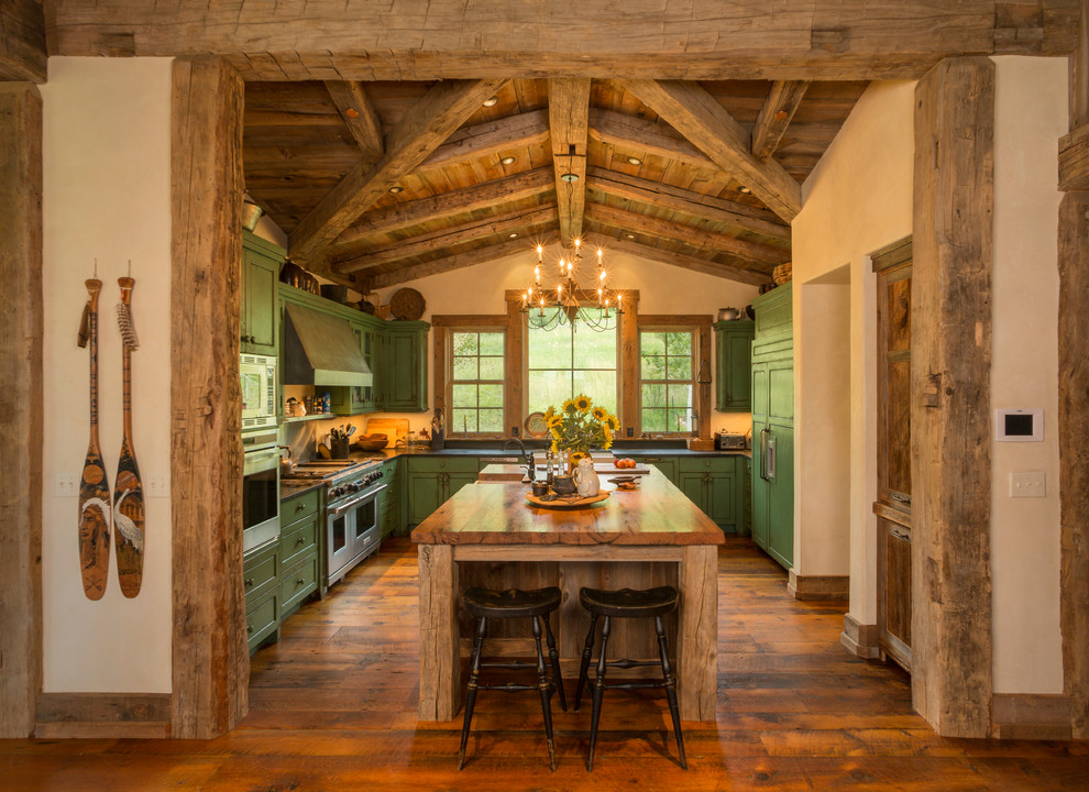 Inredning av ett rustikt u-kök, med luckor med infälld panel, gröna skåp, träbänkskiva, integrerade vitvaror, en rustik diskho, mellanmörkt trägolv och en köksö