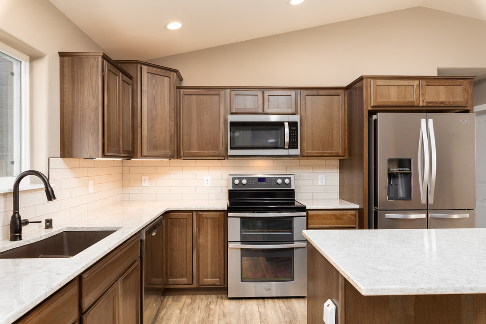 Mid-sized transitional l-shaped eat-in kitchen photo in Other with an undermount sink, flat-panel cabinets, medium tone wood cabinets, quartz countertops, white backsplash, ceramic backsplash, stainless steel appliances, an island and beige countertops