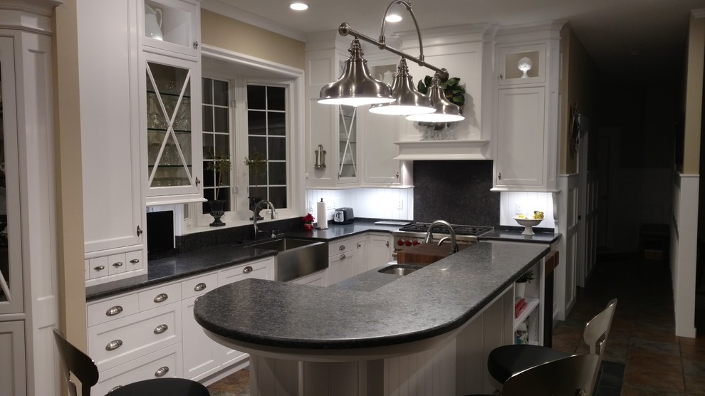 Landhaus Küche mit Landhausspüle, flächenbündigen Schrankfronten, weißen Schränken, Granit-Arbeitsplatte und Küchengeräten aus Edelstahl in Sonstige