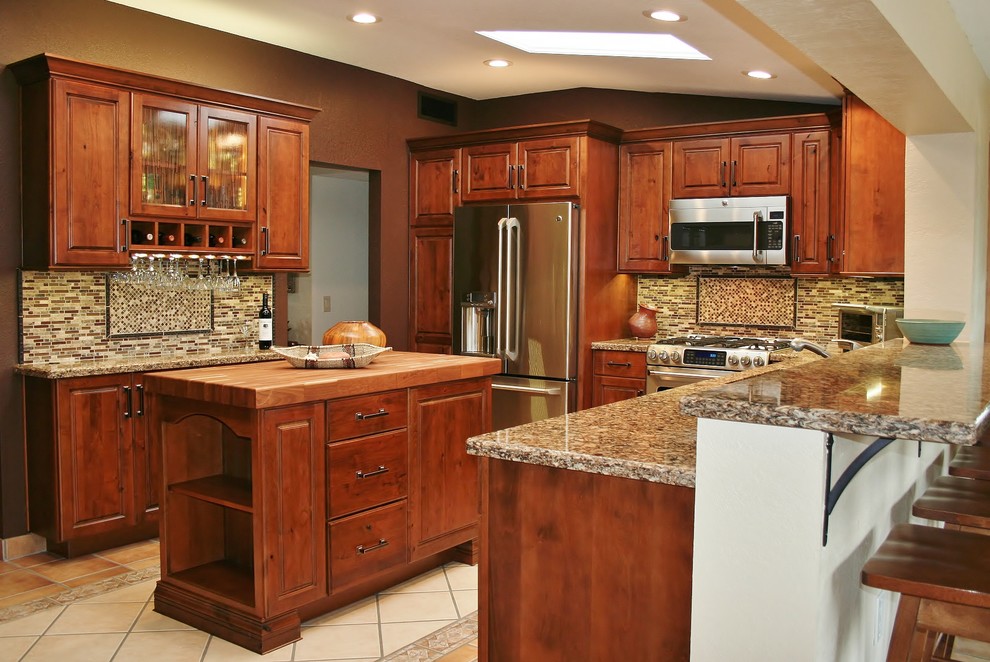 Bild på ett mellanstort amerikanskt kök, med en undermonterad diskho, luckor med infälld panel, skåp i mörkt trä, granitbänkskiva, beige stänkskydd, stänkskydd i stickkakel, rostfria vitvaror, klinkergolv i keramik och en köksö