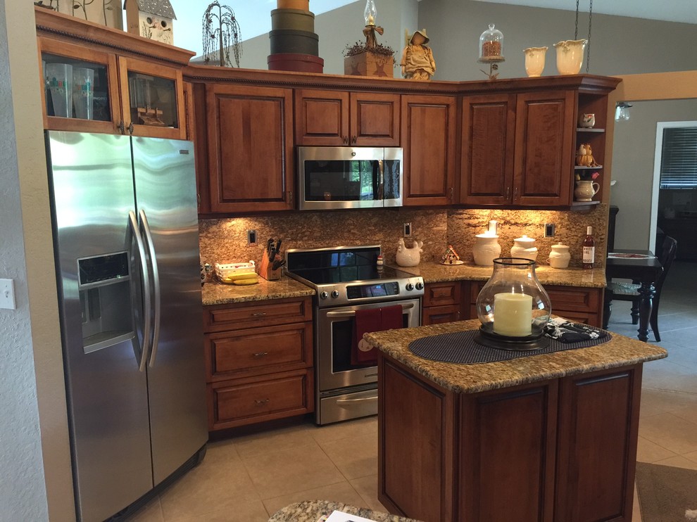 Foto de cocinas en L contemporánea de tamaño medio con puertas de armario marrones, encimera de granito, salpicadero beige, electrodomésticos de acero inoxidable y una isla