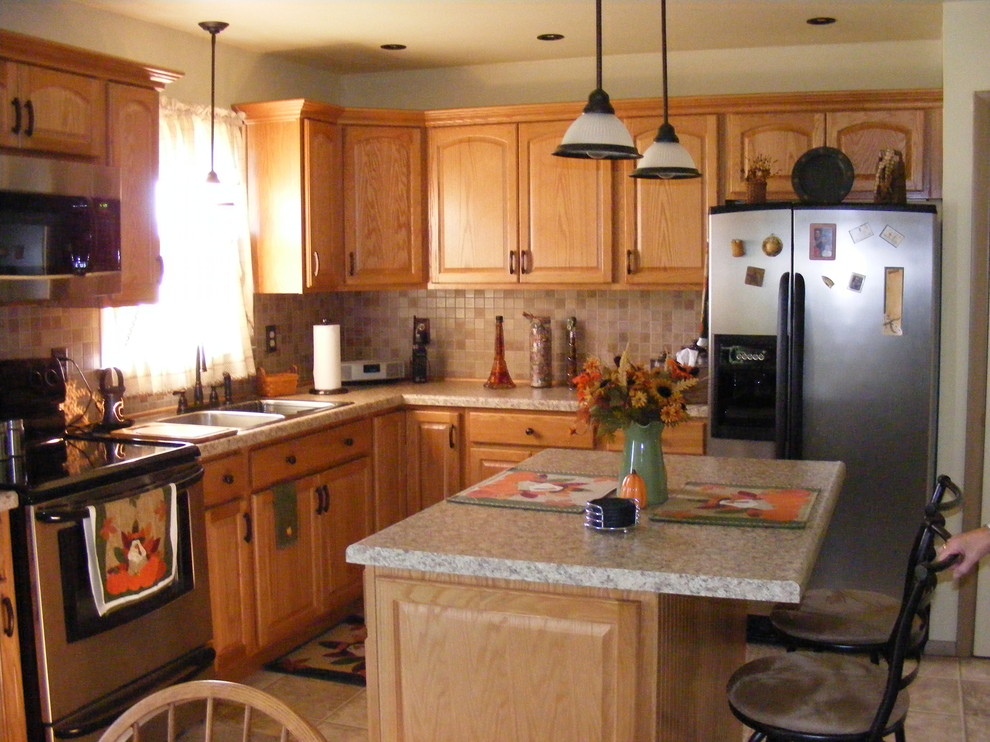 Eat-in kitchen - small transitional l-shaped ceramic tile eat-in kitchen idea in Philadelphia with a drop-in sink, raised-panel cabinets, light wood cabinets, beige backsplash, ceramic backsplash, stainless steel appliances and an island