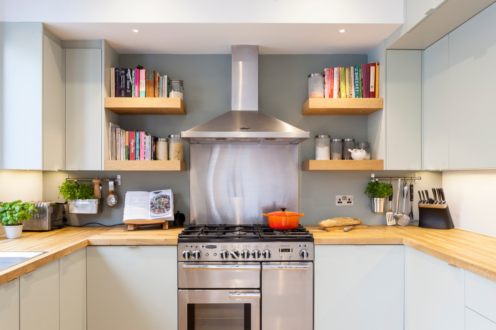 Immagine di una cucina ad U design con ante lisce, ante grigie, top in legno, paraspruzzi grigio e elettrodomestici in acciaio inossidabile