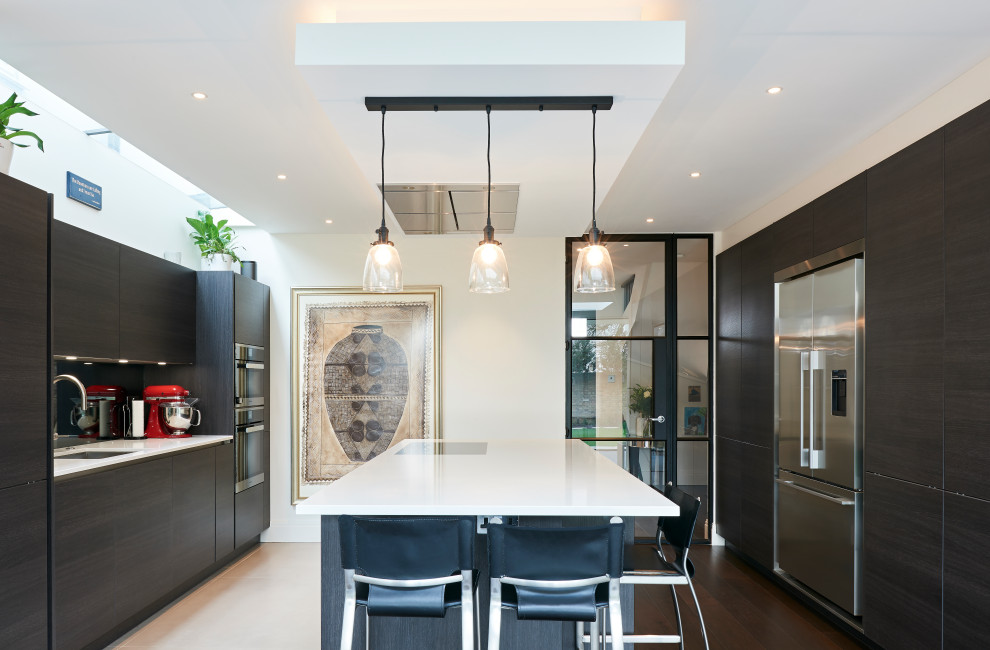 Photo of a contemporary kitchen in London with a submerged sink, flat-panel cabinets, black cabinets, black splashback, stainless steel appliances, an island, beige floors and white worktops.