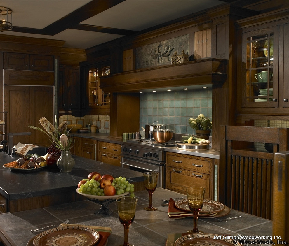 This is an example of a traditional galley kitchen/diner in Calgary with a submerged sink, flat-panel cabinets, dark wood cabinets, soapstone worktops, blue splashback and stainless steel appliances.