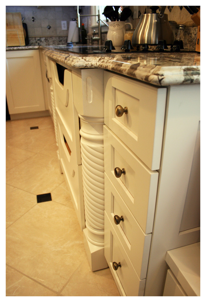 Cette image montre une cuisine américaine traditionnelle en U avec un évier encastré, un placard à porte shaker, des portes de placard blanches, un plan de travail en granite, un électroménager en acier inoxydable et îlot.