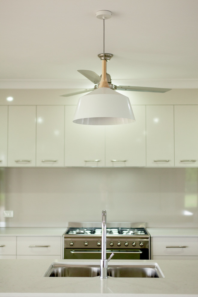 Mid-sized minimalist single-wall vinyl floor eat-in kitchen photo in Cairns with a drop-in sink, beige backsplash, glass sheet backsplash, stainless steel appliances and an island
