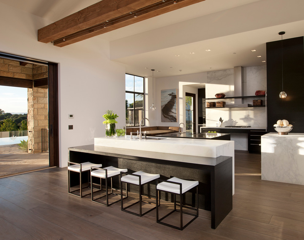 Moderne Wohnküche mit offenen Schränken, schwarzen Schränken, Küchenrückwand in Weiß, braunem Holzboden und zwei Kücheninseln in Santa Barbara