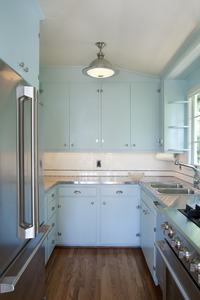 Imagen de cocinas en U tradicional pequeño con puertas de armario azules y encimera de acero inoxidable