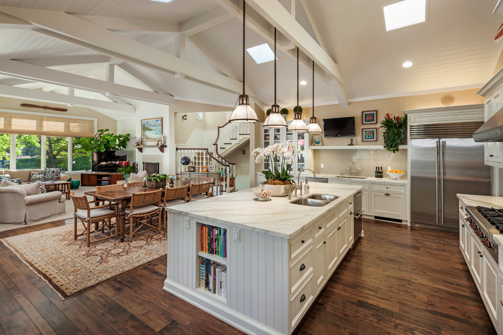 Inspiration for a large coastal u-shaped dark wood floor open concept kitchen remodel in Santa Barbara with a double-bowl sink, recessed-panel cabinets, white cabinets, marble countertops, beige backsplash, ceramic backsplash, stainless steel appliances and an island