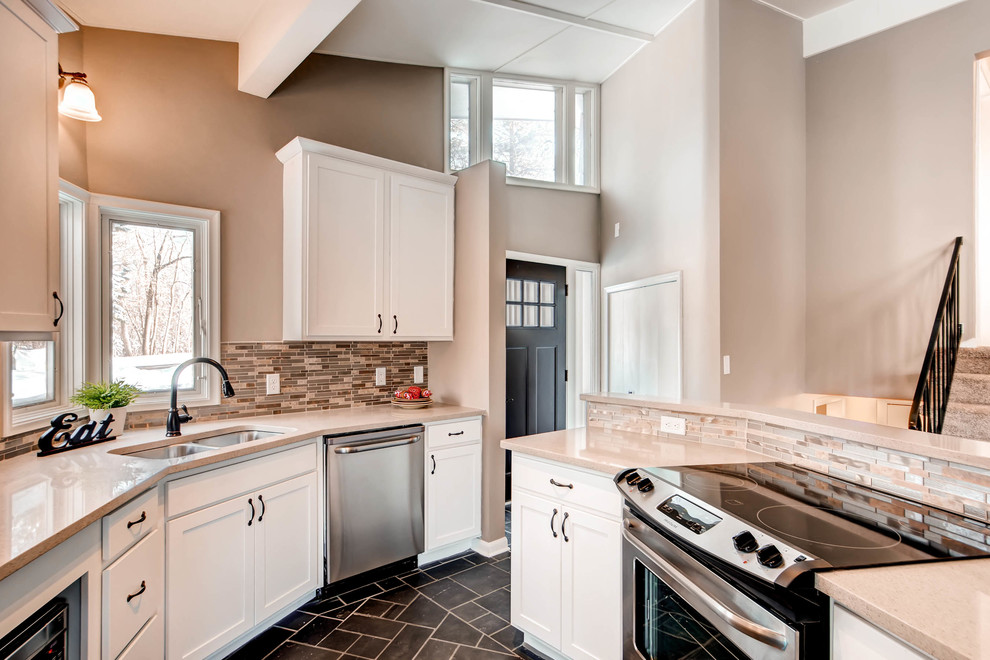 Example of a mid-sized transitional u-shaped slate floor and gray floor enclosed kitchen design in Minneapolis with an undermount sink, shaker cabinets, white cabinets, granite countertops, multicolored backsplash, matchstick tile backsplash, stainless steel appliances, a peninsula and beige countertops
