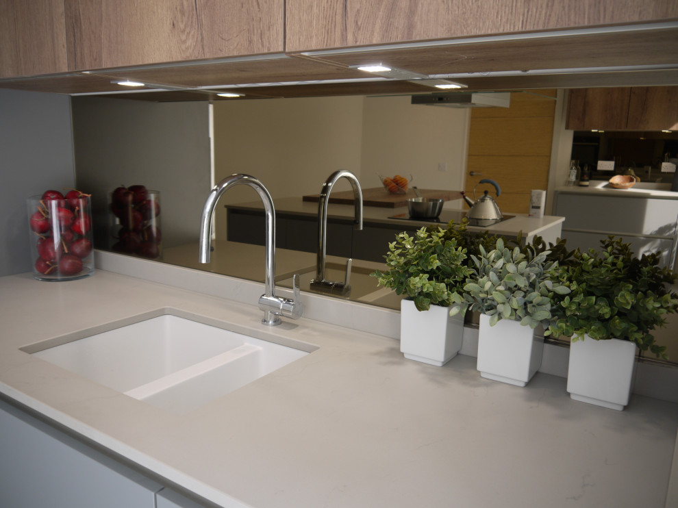 Esempio di una piccola cucina scandinava con lavello integrato, ante lisce, ante grigie, top in quarzo composito, paraspruzzi a specchio, elettrodomestici neri, pavimento in gres porcellanato, pavimento bianco e top bianco