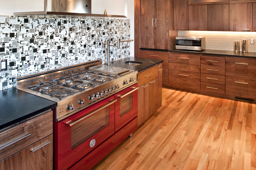 Example of a mid-sized 1950s l-shaped medium tone wood floor eat-in kitchen design in Boise with an undermount sink, flat-panel cabinets, medium tone wood cabinets, soapstone countertops, white backsplash, glass tile backsplash and colored appliances