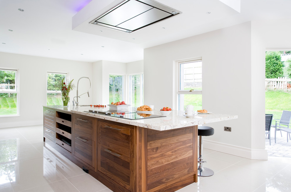 Immagine di una cucina minimalista chiusa e di medie dimensioni con lavello sottopiano, ante lisce, ante in legno bruno, top in granito, elettrodomestici in acciaio inossidabile e pavimento in gres porcellanato