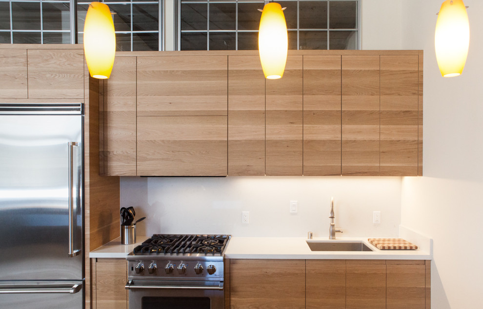 Foto på ett mellanstort industriellt kök, med släta luckor, skåp i mellenmörkt trä, vitt stänkskydd, rostfria vitvaror, betonggolv och en halv köksö