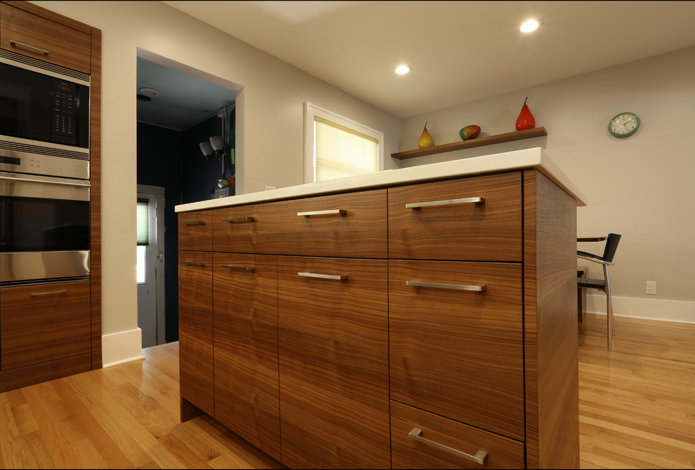 Idée de décoration pour une petite cuisine américaine design en U et bois foncé avec un placard à porte plane, îlot, un sol en bois brun et un sol marron.