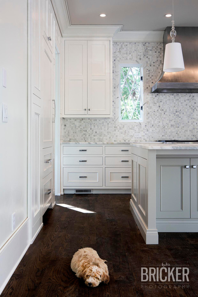 Exempel på ett stort amerikanskt kök, med en rustik diskho, luckor med infälld panel, vita skåp, marmorbänkskiva, vitt stänkskydd, stänkskydd i keramik, integrerade vitvaror, mörkt trägolv och en köksö