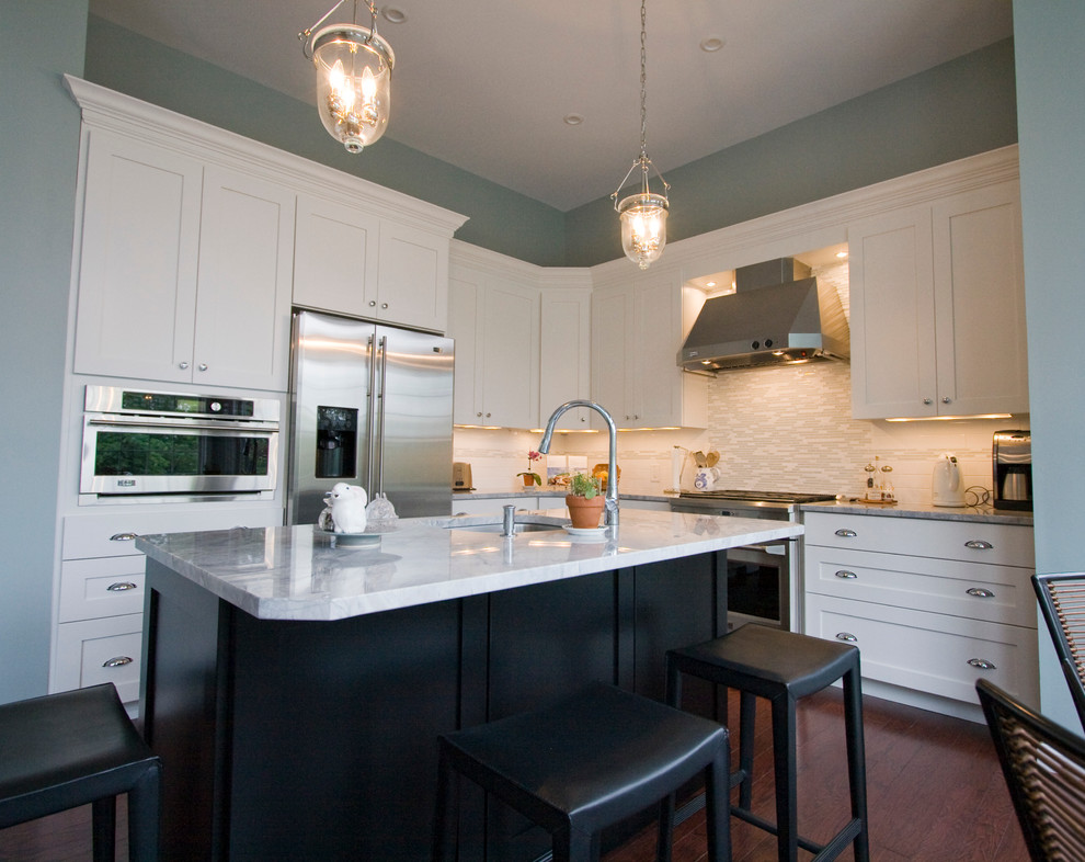 ワシントンD.C.にある中くらいなトランジショナルスタイルのおしゃれなキッチン (シェーカースタイル扉のキャビネット、白いキャビネット、珪岩カウンター、ベージュキッチンパネル、サブウェイタイルのキッチンパネル、シルバーの調理設備、濃色無垢フローリング) の写真