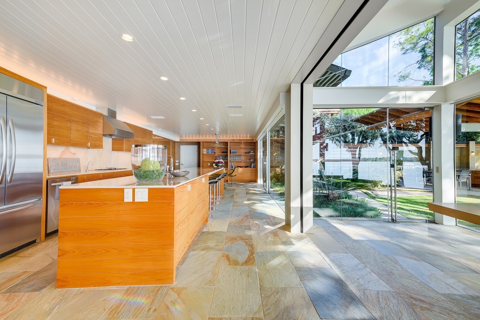 Example of a large 1960s galley slate floor eat-in kitchen design in Austin with flat-panel cabinets, an island, stainless steel appliances and onyx countertops