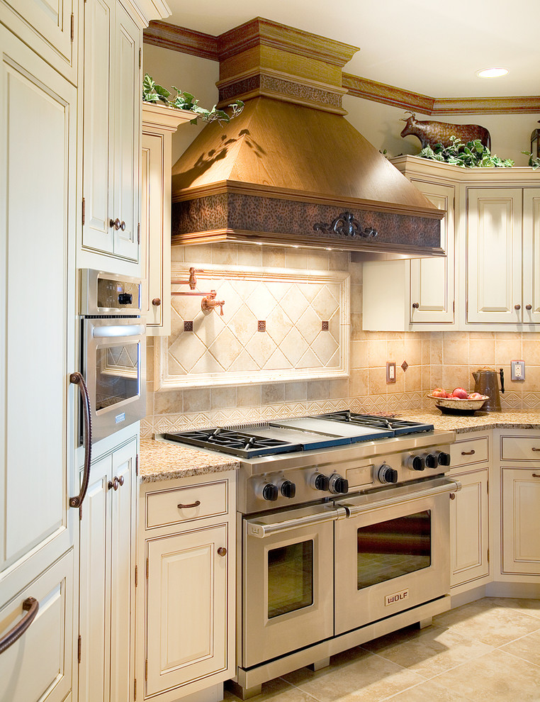 This is an example of a large rural u-shaped open plan kitchen in Chicago with a submerged sink, raised-panel cabinets, beige cabinets, beige splashback, stone tiled splashback, stainless steel appliances, ceramic flooring and multiple islands.