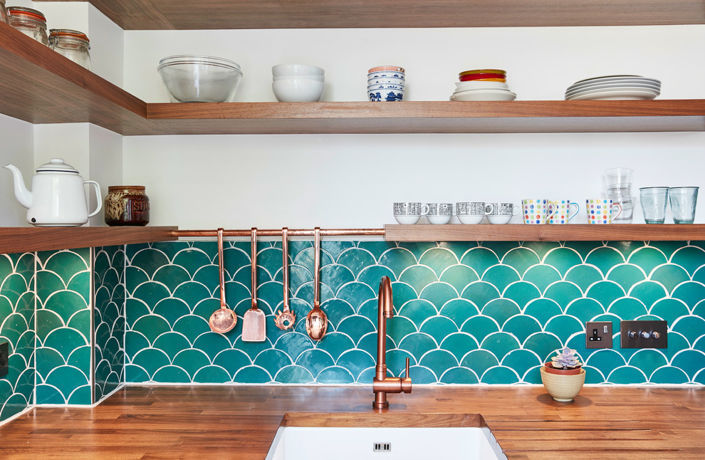 ロンドンにある高級な小さなミッドセンチュリースタイルのおしゃれなキッチン (フラットパネル扉のキャビネット、青いキャビネット、アイランドなし、木材カウンター、青いキッチンパネル、セメントタイルのキッチンパネル、シルバーの調理設備、無垢フローリング、茶色い床) の写真