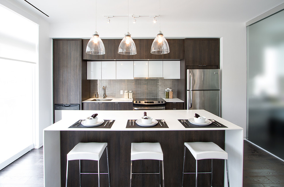 Einzeilige, Kleine Moderne Wohnküche mit Küchenrückwand in Metallic, Rückwand aus Metallfliesen, flächenbündigen Schrankfronten, dunklen Holzschränken, Küchengeräten aus Edelstahl, dunklem Holzboden, Kücheninsel, Unterbauwaschbecken und weißer Arbeitsplatte in Toronto