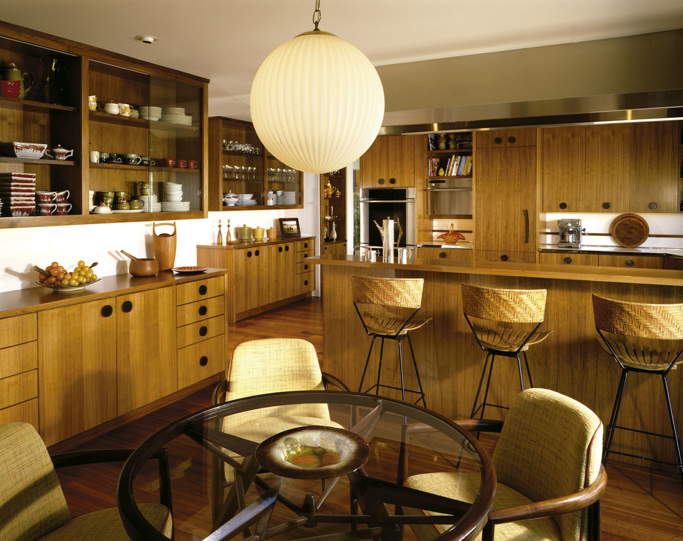 Bild på ett mellanstort 60 tals beige beige kök, med släta luckor, skåp i mellenmörkt trä, träbänkskiva, rostfria vitvaror, mellanmörkt trägolv, en halv köksö och brunt golv