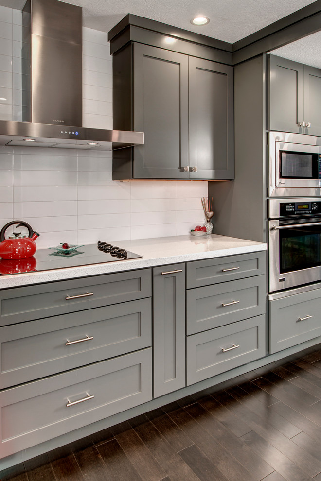 Foto di una cucina moderna di medie dimensioni con lavello sottopiano, ante in stile shaker, ante grigie, top in quarzo composito, paraspruzzi bianco, elettrodomestici in acciaio inossidabile e parquet scuro