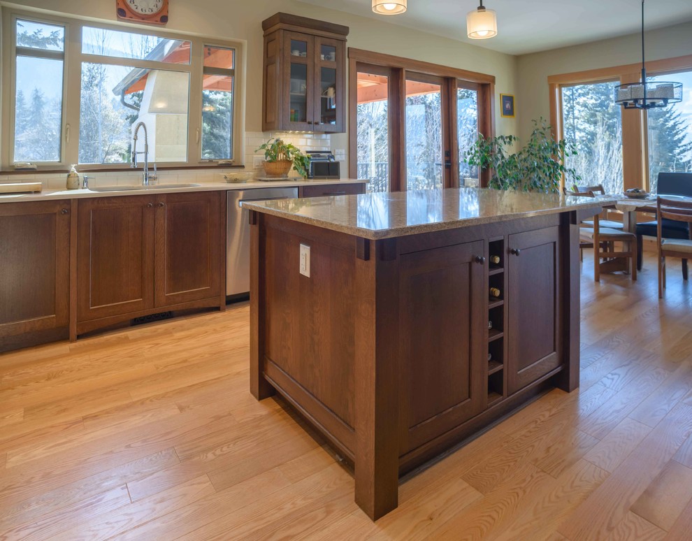 Example of a mid-sized arts and crafts u-shaped medium tone wood floor eat-in kitchen design in Vancouver with an undermount sink, shaker cabinets, dark wood cabinets, quartz countertops, white backsplash, subway tile backsplash, stainless steel appliances and an island