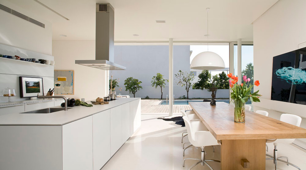 На фото: кухня в стиле модернизм с обеденным столом, врезной мойкой, плоскими фасадами и белыми фасадами с