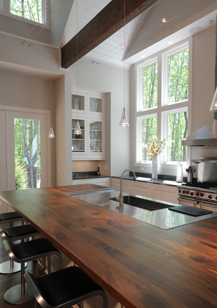 Example of a minimalist u-shaped dark wood floor open concept kitchen design in San Francisco with a single-bowl sink, shaker cabinets, white cabinets, wood countertops, gray backsplash, stone slab backsplash, stainless steel appliances and an island