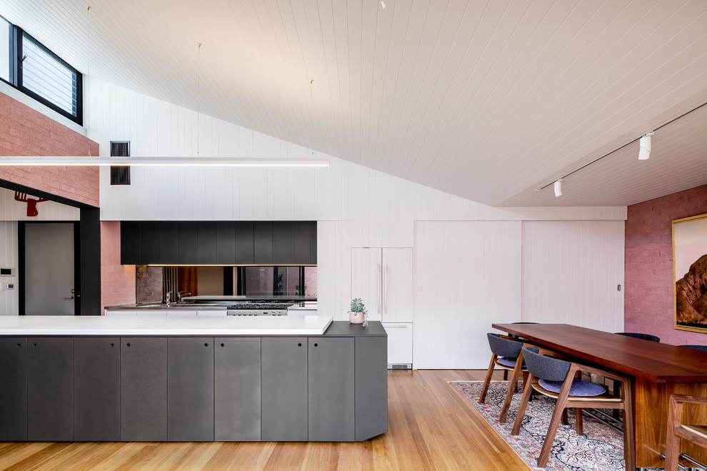 Zweizeilige Moderne Wohnküche mit flächenbündigen Schrankfronten, grauen Schränken, Elektrogeräten mit Frontblende, braunem Holzboden, Kücheninsel, braunem Boden und weißer Arbeitsplatte in Adelaide