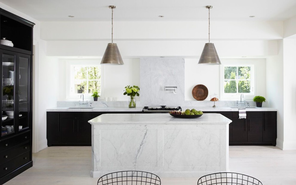 Inredning av ett modernt stort linjärt kök och matrum, med en undermonterad diskho, luckor med profilerade fronter, svarta skåp, marmorbänkskiva, vitt stänkskydd, stänkskydd i sten, ljust trägolv, en köksö och beiget golv