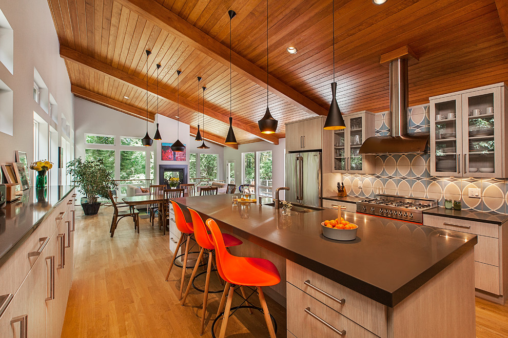 Photo of a midcentury open plan kitchen in Detroit with a submerged sink, glass-front cabinets, light wood cabinets, multi-coloured splashback, stainless steel appliances, light hardwood flooring, an island, composite countertops and ceramic splashback.