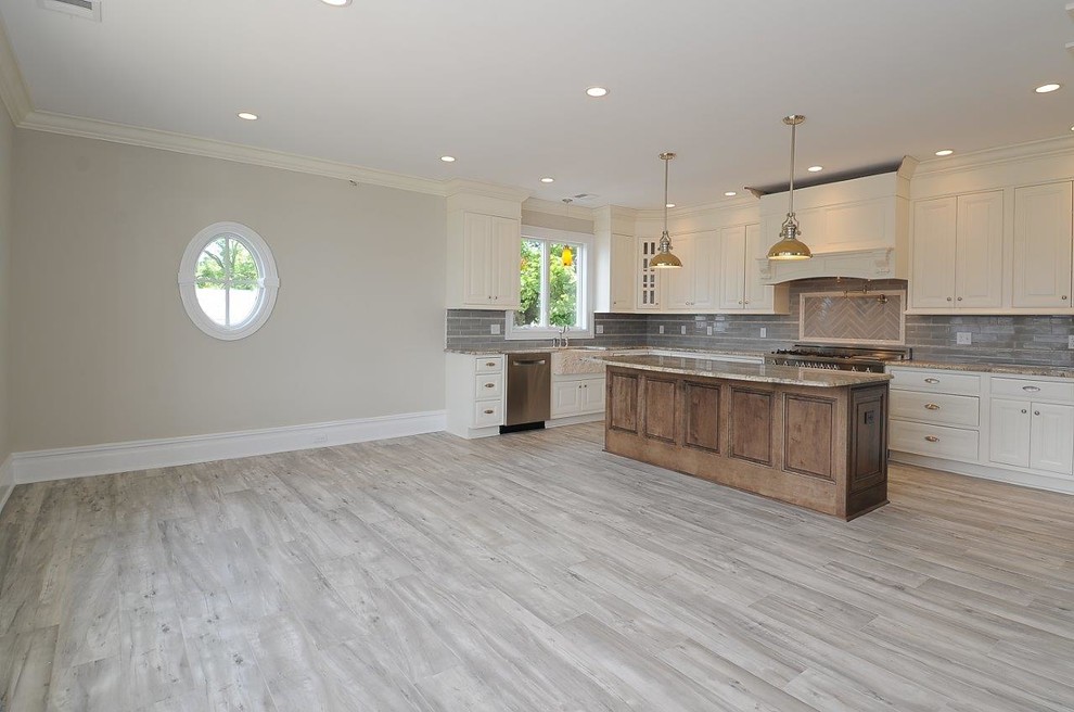 Example of a mid-sized classic u-shaped porcelain tile and gray floor eat-in kitchen design in New York with a farmhouse sink, beaded inset cabinets, white cabinets, granite countertops, gray backsplash, subway tile backsplash, stainless steel appliances, an island and multicolored countertops