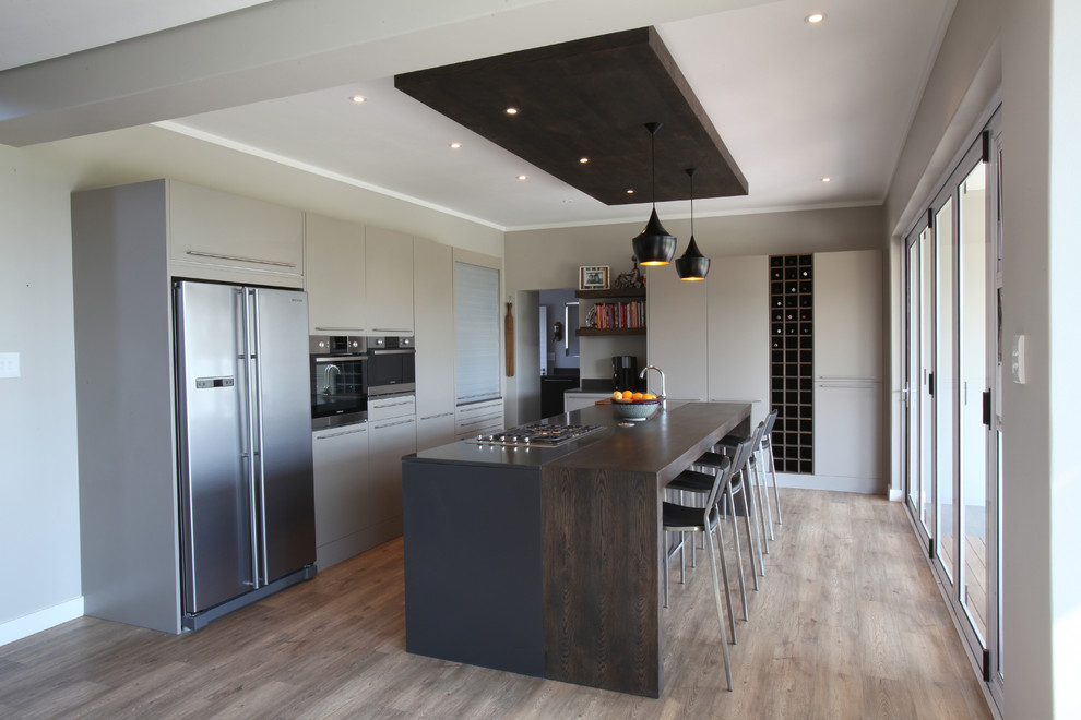 Cette photo montre une cuisine parallèle tendance avec un placard à porte plane, des portes de placard grises, un plan de travail en bois et un électroménager en acier inoxydable.