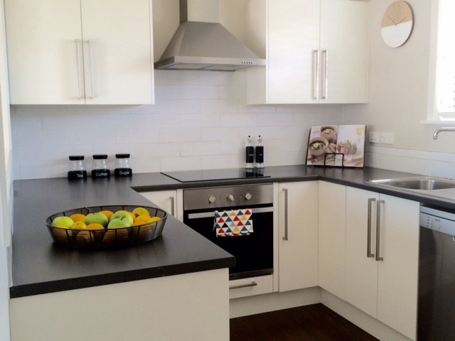 Imagen de cocina comedor minimalista pequeña con armarios con paneles lisos, puertas de armario blancas, península y suelo negro