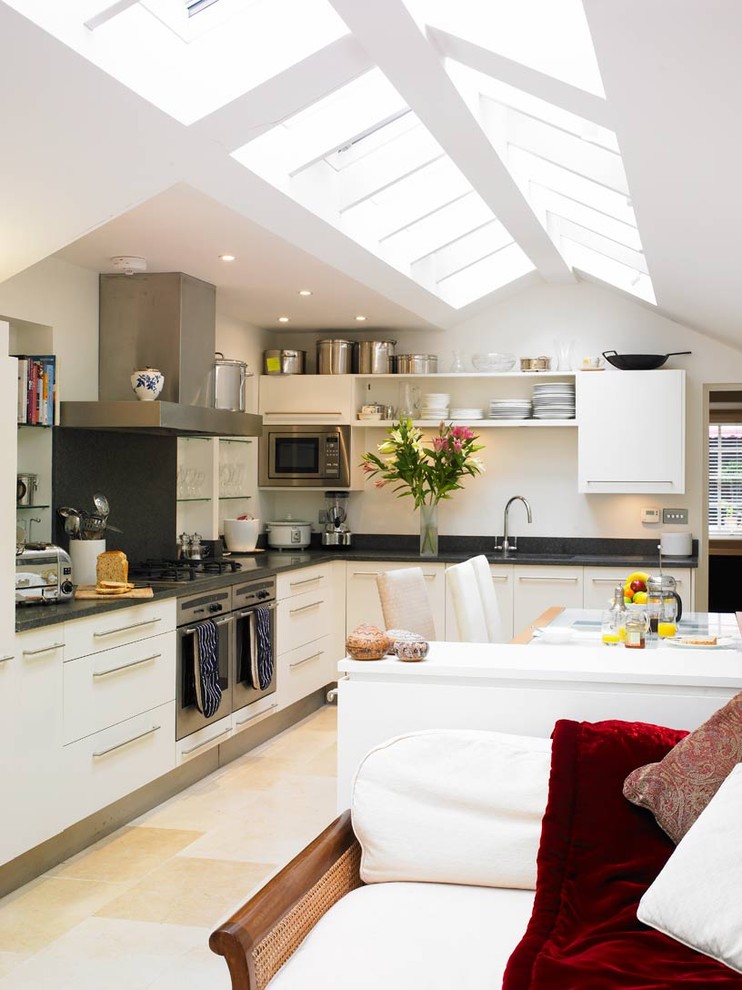 Design ideas for a contemporary l-shaped open plan kitchen in London with stainless steel appliances and white cabinets.