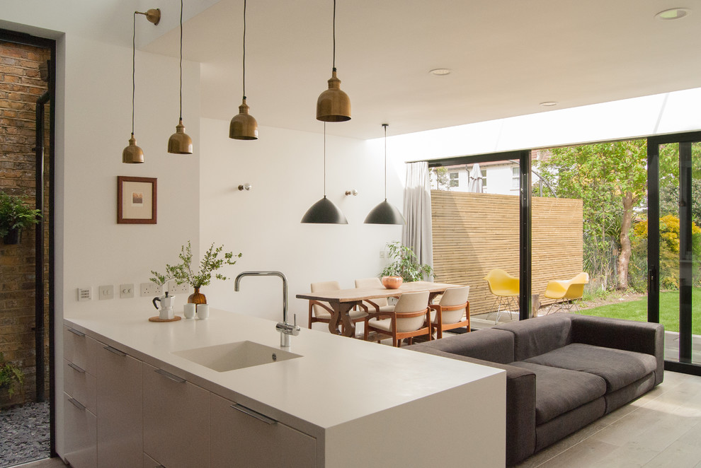 Example of a trendy kitchen design in London with an integrated sink, flat-panel cabinets and a peninsula