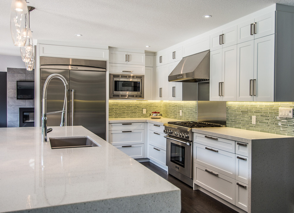 Eat-in kitchen - contemporary u-shaped eat-in kitchen idea in Toronto with an undermount sink, shaker cabinets, white cabinets, quartz countertops, green backsplash, glass sheet backsplash and stainless steel appliances