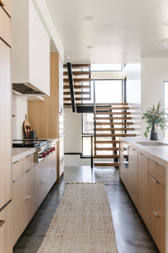 Exempel på ett mellanstort modernt grå linjärt grått kök med öppen planlösning, med en undermonterad diskho, släta luckor, skåp i ljust trä, bänkskiva i kvartsit, grått stänkskydd, rostfria vitvaror, betonggolv, en köksö och grått golv