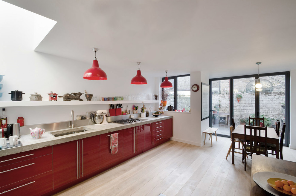 Immagine di una cucina design di medie dimensioni con lavello a doppia vasca, ante rosse, top in cemento, paraspruzzi a effetto metallico, elettrodomestici in acciaio inossidabile e nessuna isola