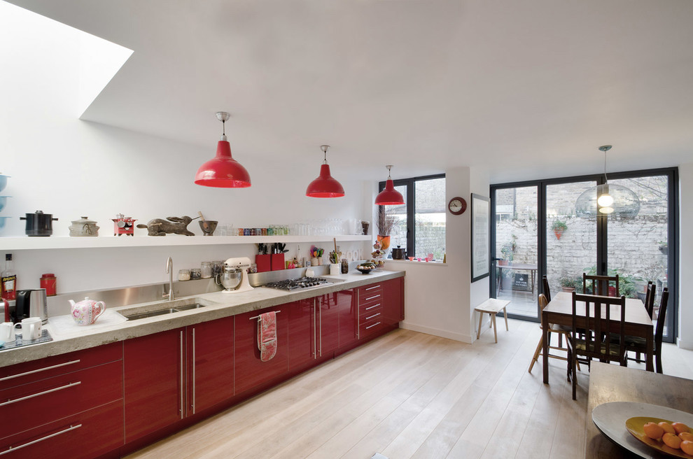 Inspiration for a mid-sized contemporary single-wall eat-in kitchen remodel in London with a double-bowl sink, red cabinets, concrete countertops, metallic backsplash, stainless steel appliances and no island