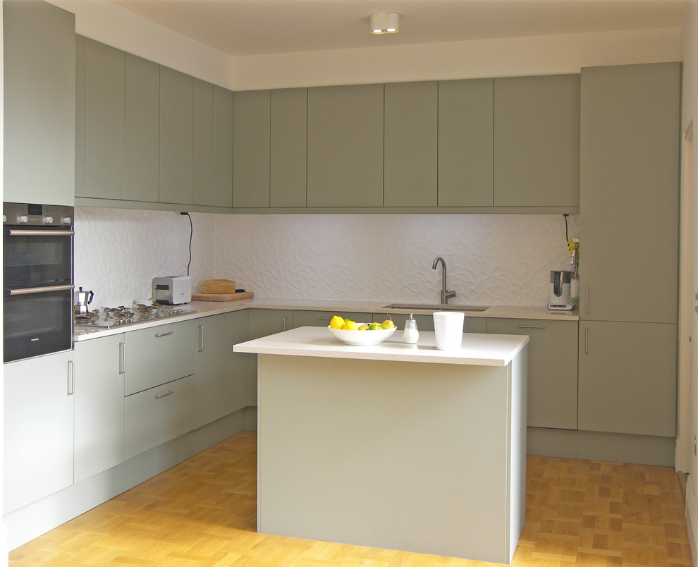 Aménagement d'une cuisine moderne avec un placard à porte plane, des portes de placard grises, un plan de travail en quartz, une crédence blanche, une crédence en carreau de porcelaine et un sol en bois brun.