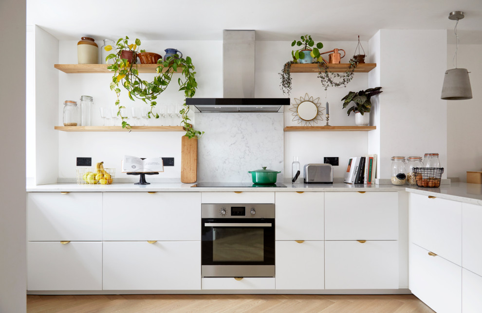 Exempel på ett modernt l-kök, med släta luckor, vita skåp, grått stänkskydd, rostfria vitvaror, ljust trägolv och beiget golv
