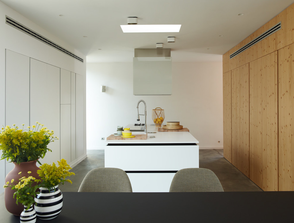 Esempio di una cucina design chiusa e di medie dimensioni con ante lisce, ante in legno scuro, top in superficie solida, elettrodomestici in acciaio inossidabile e pavimento in cemento