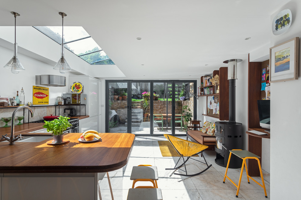 ロンドンにあるエクレクティックスタイルのおしゃれなキッチン (フラットパネル扉のキャビネット、白いキャビネット、黒い調理設備、ベージュの床、茶色いキッチンカウンター) の写真