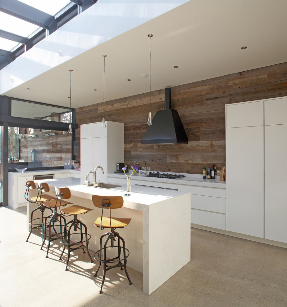 Modern inredning av ett stort kök, med en undermonterad diskho, släta luckor, vita skåp och en köksö