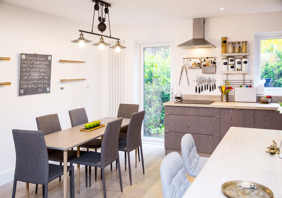 This is an example of a medium sized contemporary u-shaped open plan kitchen in London with a submerged sink, flat-panel cabinets, grey cabinets, wood worktops, white splashback, window splashback, integrated appliances, light hardwood flooring, a breakfast bar and white floors.