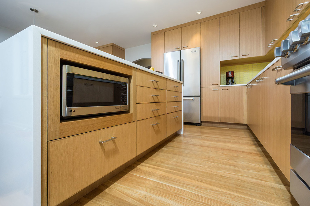 Exempel på ett modernt kök, med släta luckor, skåp i mellenmörkt trä, bänkskiva i kvarts, gult stänkskydd, stänkskydd i keramik, rostfria vitvaror, mellanmörkt trägolv och en köksö